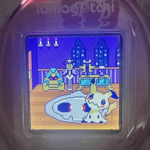 Puede incluir: Un dispositivo Tamagotchi rosa con una pantalla digital que muestra una escena pixelada. La escena presenta un personaje de dibujos animados, muebles y una alfombra estampada. El dispositivo tiene la palabra "Tamagotchi" impresa en la parte superior.