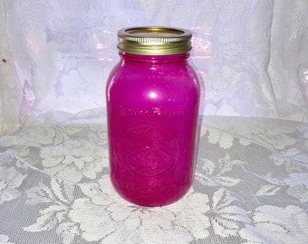 May include: A bright pink glass jar with a gold lid. The jar has a white label with the text "Ball" and "Wide Mouth" printed on it.