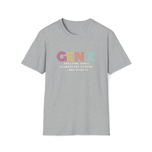 Gildan softstyle tee in Sport Grey that says Gen X in colorful large letters over smaller white letters that say Adulting Since Elementary School...and Over It