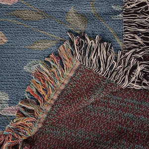 K&ouml;nnte beinhalten: Nahaufnahme einer gewebten Wandteppich mit einem blauen und gr&uuml;nen Muster. Der Wandteppich hat einen Fransenrand mit einer Mischung aus Farben, darunter Rot, Orange, Gelb und Blau.