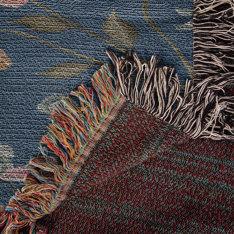 K&ouml;nnte beinhalten: Nahaufnahme einer gewebten Wandteppich mit einem blauen und gr&uuml;nen Muster. Der Wandteppich hat einen Fransenrand mit einer Mischung aus Farben, darunter Rot, Orange, Gelb und Blau.