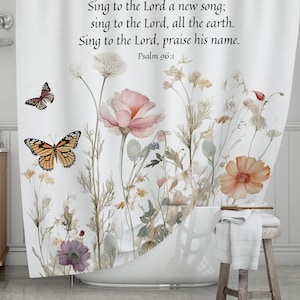 May include: White shower curtain featuring watercolor illustrations of flowers and butterflies. The design includes a large pink flower, orange and brown butterflies, and text from Psalm 96:1.
