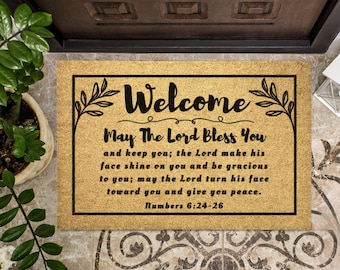 May include: A brown coir doormat with black text that reads "Welcome May The Lord Bless You and keep you; the Lord make his face shine on you and be gracious to you; may the Lord turn his face toward you and give you peace. Numbers 6:24-26"