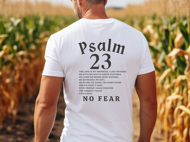 Może przedstawiać: Biała koszulka z czarnym tekstem, kt&oacute;ry brzmi "Psalm 23" i wersetem z Biblii. Tekst jest wyśrodkowany na plecach koszulki.
