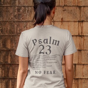 Może przedstawiać: Jasnoszary t-shirt z nadrukiem "Psalm 23" na plecach. Tekst jest w czarnej czcionce szeryfowej. Tekst zawiera werset z Biblii, Psalm 23.