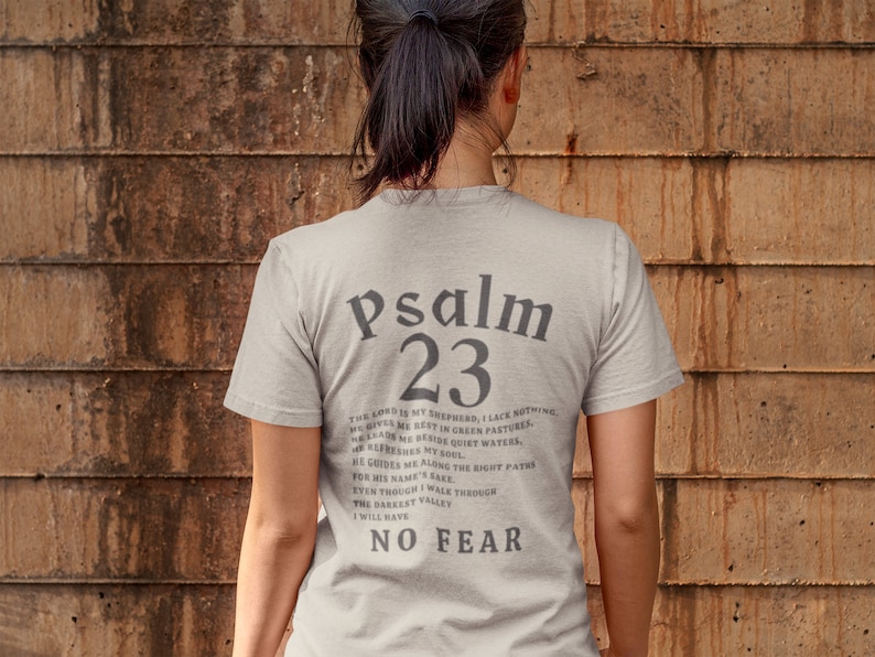 Może przedstawiać: Jasnoszary t-shirt z nadrukiem "Psalm 23" na plecach. Tekst jest w czarnej czcionce szeryfowej. Tekst zawiera werset z Biblii, Psalm 23.