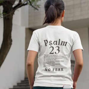 Może przedstawiać: Biała koszulka z czarnym tekstem, kt&oacute;ry brzmi "Psalm 23" i wersetem z Biblii. Tekst jest wyśrodkowany na plecach koszulki.