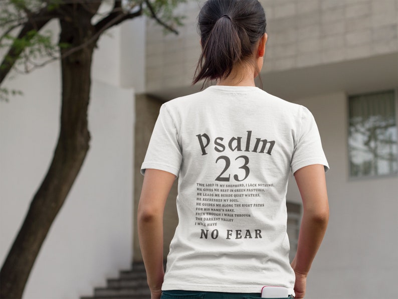 Może przedstawiać: Biała koszulka z czarnym tekstem, kt&oacute;ry brzmi "Psalm 23" i wersetem z Biblii. Tekst jest wyśrodkowany na plecach koszulki.
