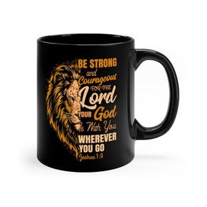 May include: Black coffee mug with a lion graphic and the text "BE STRONG and Courageous FOR THE Lord YOUR God Is With You WHEREVER YOU GO Joshua 1:9".