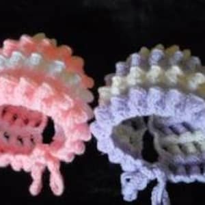 May include: Two crocheted baby hats, one pink and one purple, with white stripes. The hats have a ruffled edge and are tied with a ribbon.