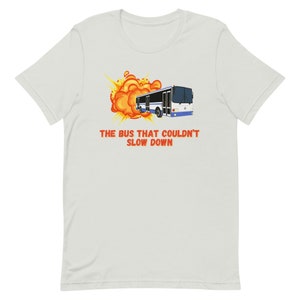 May include: A white bus with blue accents is engulfed in a large orange and yellow explosion. The text "THE BUS THAT COULDN'T SLOW DOWN" is written in red below the bus.