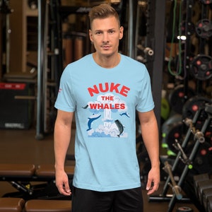 May include: A light blue t-shirt with a graphic of a mushroom cloud and whales with the text "NUKE THE WHALES" in red.