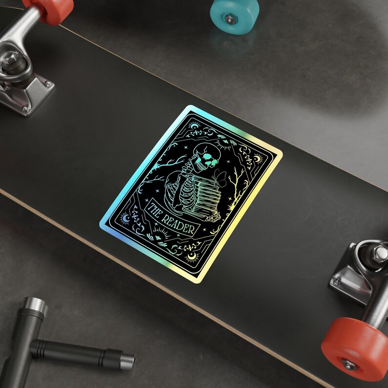 Holographic tarot card sticker featuring a skeleton holding a stack of books with a butterfly atop, surrounded by celestial stars and tree branches. Perfect for laptops, journals, water bottles, and scrapbooks. Ideal gift for readers and book lovers.