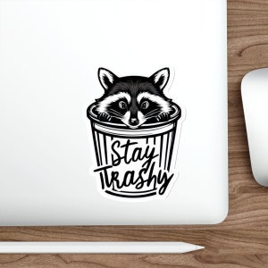 Water resistant feral raccoon trash panda funny die cut sticker with Stay Trashy slogan, perfect for laptops, tumblers, water bottles, journals, and more! Raccoon gifts for animal lovers in their feral era.
