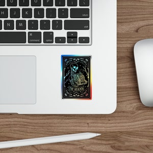 Holographic tarot card sticker featuring a skeleton holding a stack of books with a butterfly atop, surrounded by celestial stars and tree branches. Perfect for laptops, journals, water bottles, and scrapbooks. Ideal gift for readers and book lovers.