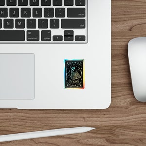 Holographic tarot card sticker featuring a skeleton holding a stack of books with a butterfly atop, surrounded by celestial stars and tree branches. Perfect for laptops, journals, water bottles, and scrapbooks. Ideal gift for readers and book lovers.