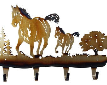 May include: Metal wall mounted key holder featuring a silhouette of two horses running through a field with trees. The key holder has four hooks.