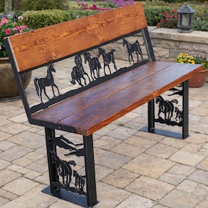 May include: A wooden bench with a dark stain, featuring a backrest and seat. The bench has black metal supports and decorative cutouts of horses along the back and legs. The bench is outdoors on a stone patio.