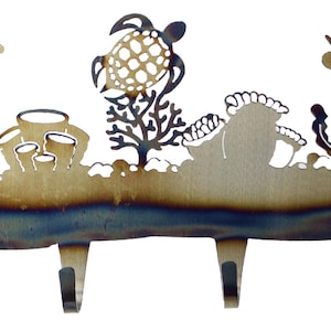 May include: Metal wall-mounted key holder with a sea turtle, coral, and seaweed design. The holder has four hooks for hanging keys or other items.