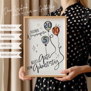 May include: A framed print with a light wood frame. The print features three balloons with the numbers 5, 10, and 20, and the words "Alles Gute zum Geburtstag." The print also includes the text "Dein Geschenk mehr als nur ein Geldbetrag."