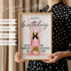 Puede incluir: Un cuadro con una ilustraci&oacute;n de una botella de champ&aacute;n rosa, las palabras "Happy Birthday" en cursiva y el n&uacute;mero "50". La impresi&oacute;n incluye texto en alem&aacute;n y detalles de confeti. Una persona con un vestido de lunares blancos y negros sostiene el cuadro.