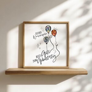 May include: A framed print with a wooden frame featuring three balloons with the numbers 5, 10, and 20. The print has the text "Kleiner Wunscherf&uuml;ller" and "Alles Gute zum Geburtstag" in black script.