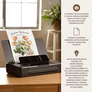May include: A black inkjet printer with a printed wedding card featuring a vintage green car, heart-shaped balloons, and floral arrangements. The card reads "Herzlichen Gl&uuml;ckwunsch zur Hochzeit". The printer sits on a wooden surface.