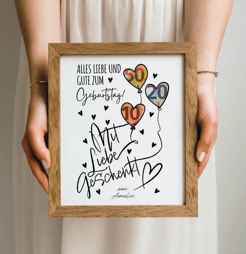 May include: A framed print with a wooden frame, featuring a birthday message in German. The artwork includes heart-shaped balloons with the numbers 10, 20, and 50, along with black heart accents and the words "Alles Liebe und Gute zum Geburtstag!" and "Mit Liebe geschenkt!"