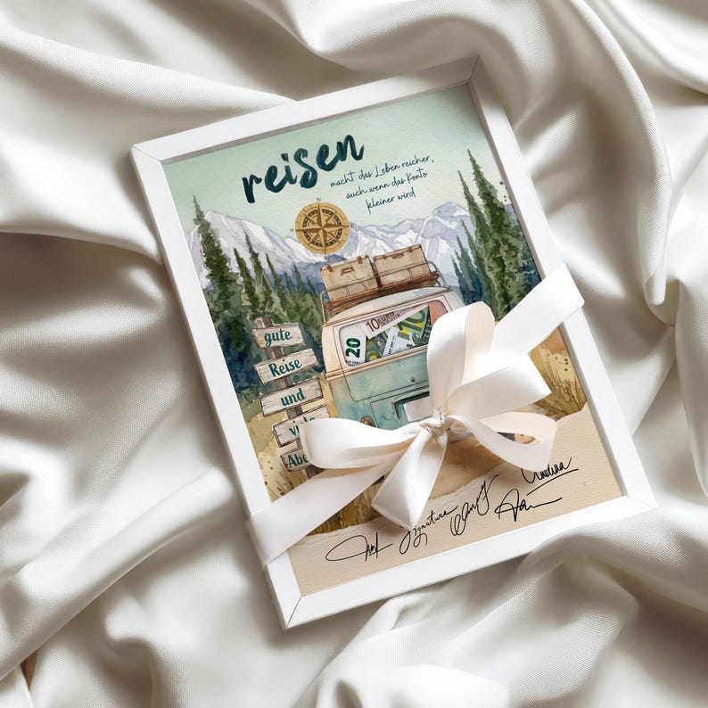 May include: A framed print featuring a watercolour illustration of a vintage van, mountains, and a compass. The text reads "reisen macht das Leben reicher, auch wenn das Konto kleiner wird" and "gute Reise und viele Abenteuer". A white ribbon is tied around the frame.