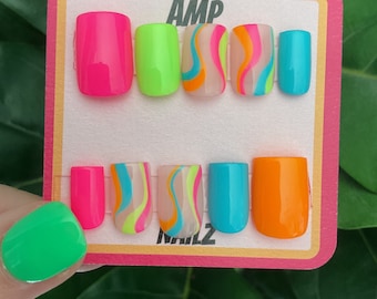 May include: A set of ten press-on nails with a variety of colors and designs. The nails are arranged in two rows of five. The colors include pink, green, blue, orange, and white. The designs include swirls and stripes. The nails are labeled "AMP NAILS".