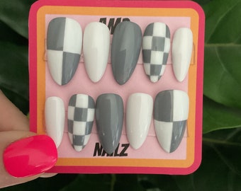 May include: Set of ten gray and white checkerboard patterned press-on nails. The nails are in a pink and orange display card with the text "AMP NAILZ".