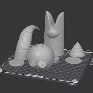 Könnte beinhalten: Eine Sammlung von 3D-gedruckten Objekten in verschiedenen Formen und Größen. Enthält ein gebogenes Horn, eine hohe, spitze Struktur mit einem Auge, eine Kugel mit Brille, einen gestuften Kegel und mehrere kreisförmige Scheiben. Die Objekte sind grau.