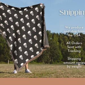 May include: A person holding up a black woven throw blanket with a white skull pattern. The blanket has fringe on the edges. The person is standing in a grassy field with trees in the background. The text "Shipping" is written in white letters on a black background above the person's head. The text below the person says "We produce and ship from the USA. All Orders Sent with Tracking. Shipping amount varies by weight."