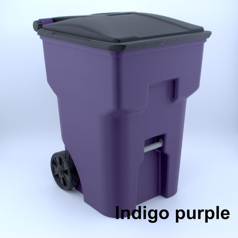 K&ouml;nnte beinhalten: Ein rollender M&uuml;lleimer in Indigolila mit einem schwarzen Deckel. Der Eimer hat zwei R&auml;der und einen Griff f&uuml;r den einfachen Transport. Der Text "Indigo purple" ist auf der Vorderseite aufgedruckt.