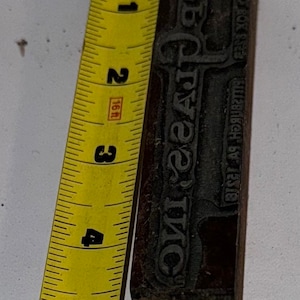 May include: A vintage wood printing block with the text "C.O.C. INC. " and "ROYAL TYPE" in raised letters. The block is approximately 4 inches tall and is made of dark wood.