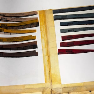 May include: An open file folder with multiple paper inserts. The inserts contain various colored labels with the text "MTD" and other text. The labels are brown, yellow, gray, and red. The folder is yellowed with age.