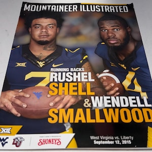 May include: A magazine cover featuring two football players in navy and gold uniforms. The text reads "MOUNTAINEER ILLUSTRATED" and highlights "RUSHEL SHELL & WENDELL SMALLWOOD". The cover also includes the text "West Virginia vs. Liberty September 12, 2015".