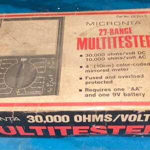 May include: A brown cardboard box with a red border and the text "MICRONTA 27-RANGE MULTITESTER" in white. The box features a black and silver multimeter with a 4-inch (10 cm) color-coded mirrored meter. The box also includes the text "30,000 OHMS/VOLT DC" in white.