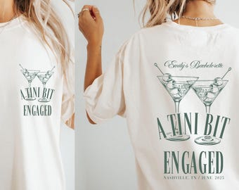 May include: Cream-colored t-shirt with a green martini glass graphic and the text "A TINI BIT ENGAGED." The back of the shirt features the text "Emily's Bachelorette" and the same graphic, with "NASHVILLE, TN / JUNE 2025" below.