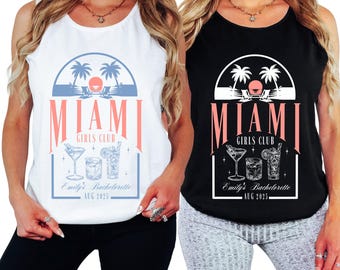 May include: Two sleeveless tank tops, one white and one black, featuring a Miami Girls Club design. The design includes palm trees, cocktails, and the text "Emily's Bachelorette AUG 2025". The tops are ideal for a bachelorette party.