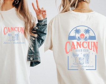 May include: Two white t-shirts with a graphic design featuring the text "Cancun Beach Club" and a palm tree silhouette. The text "Lauren's Bachelorette 2024" is also included on the design.