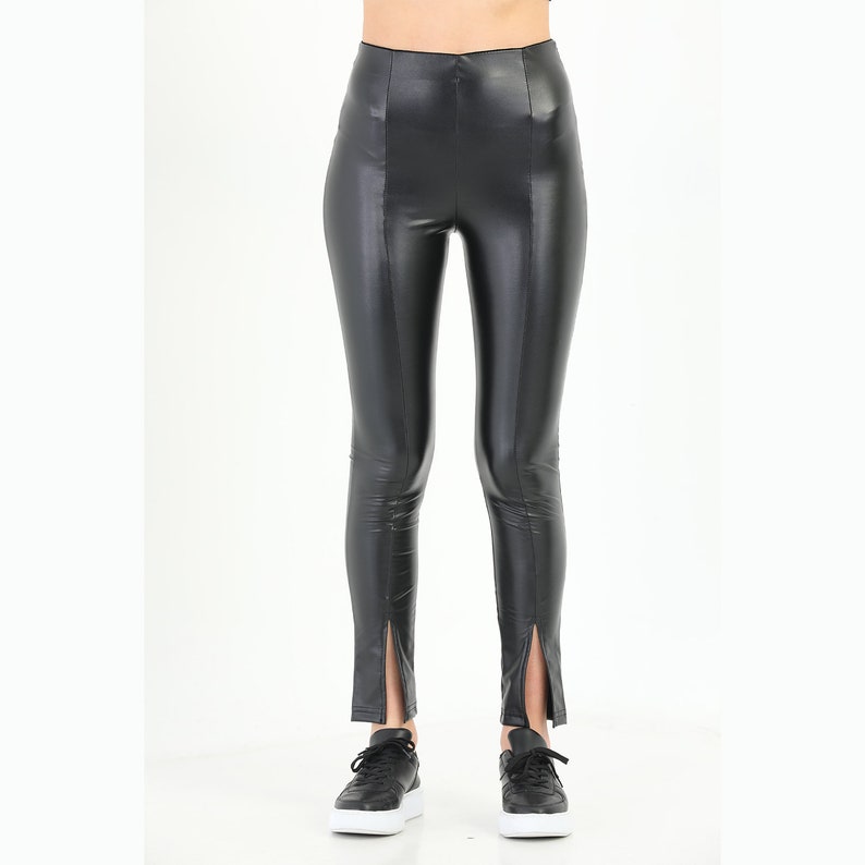 May include: Black faux leather leggings with a high waist and side slits at the ankles.
