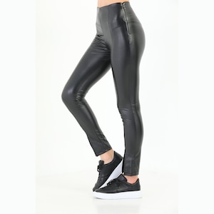 May include: Black faux leather leggings with a zipper detail on the side seams.