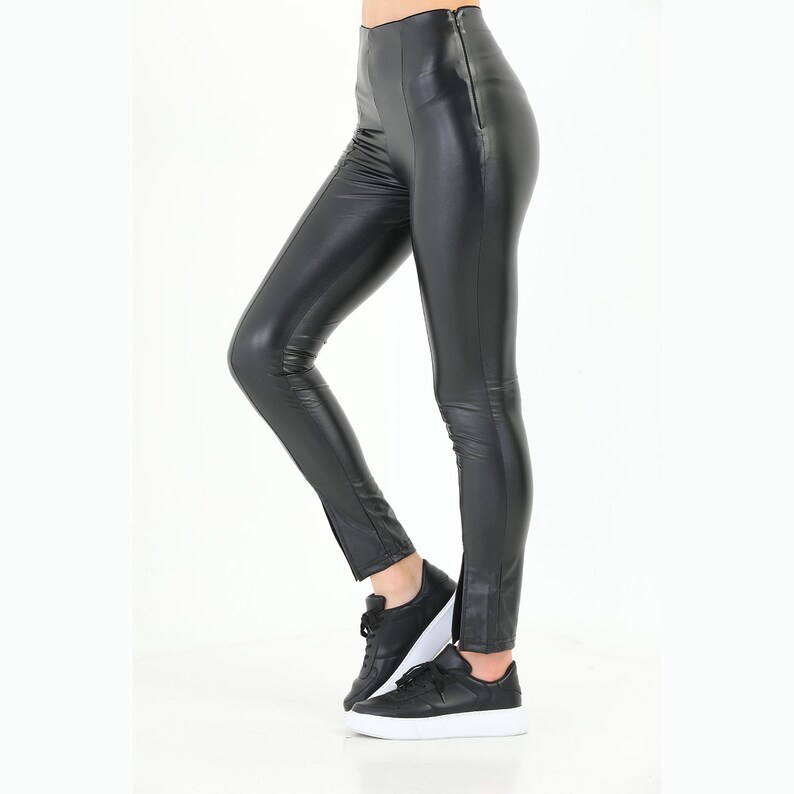 May include: Black faux leather leggings with a zipper detail on the side seams.