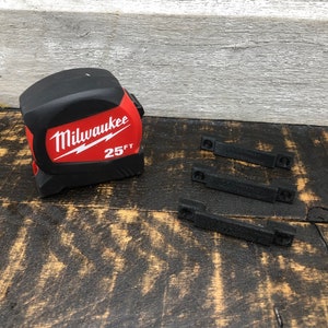 May include: A red and black Milwaukee 25ft tape measure with three black plastic clips.