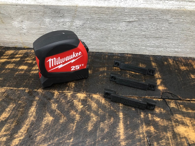 May include: A red and black Milwaukee 25ft tape measure with three black plastic clips.