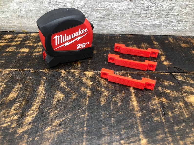 May include: A black and red Milwaukee 25 ft tape measure with three red plastic clips.