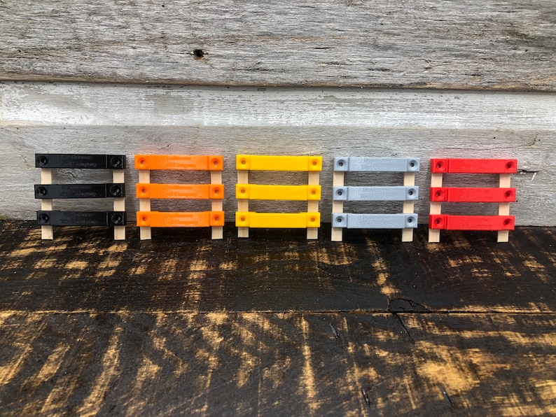 May include: Five small wooden frames with different coloured plastic inserts. The frames are arranged in a row from left to right: black, orange, yellow, grey, and red.