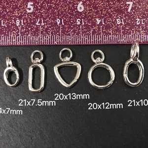 May include: Five silver metal jump rings of different shapes and sizes. The rings are measured in millimeters and the measurements are listed below each ring. The measurements are: 14x7mm, 21x7.5mm, 20x13mm, 20x12mm, and 21x10mm.