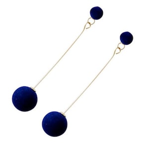 Può includere: Un paio di orecchini lunghi dorati con ciondoli a sfera in velluto blu.